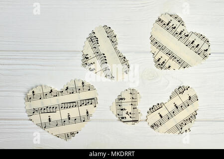 Cuori di carta con note musicali. Set di cuori di carta con note musicali su luce sullo sfondo di legno. Foto Stock