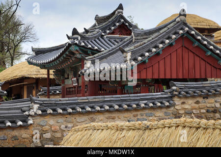 A piastrelle a padiglione tetto al Yangdong Folk Village nei pressi di Gyeongju, Corea del Sud, ha un intricato tetto, il muretto in pietra; nelle vicinanze case dal tetto di paglia sono Foto Stock