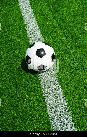 Pallone da calcio classico bianco e nero con la linea verde erba artificiale Foto Stock