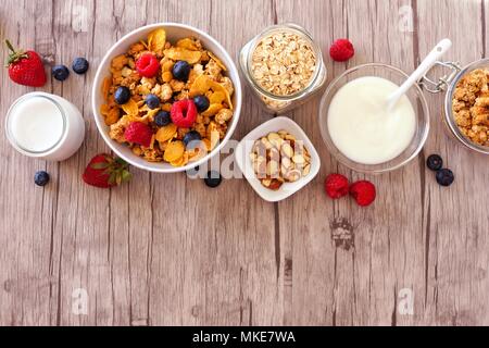 Cereali e gli ingredienti per una sana colazione formando un bordo superiore su un sfondo di legno. Vista dall'alto. Copia dello spazio. Foto Stock