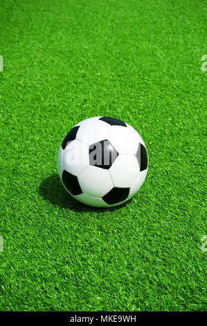 Pallone da calcio classico bianco e nero su verde erba artificiale, da soli Foto Stock