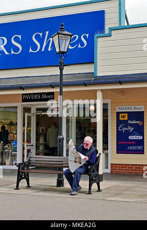 L'uomo si è seduto su un giornale di lettura da banco presso Affinity Outlets(ex Freeport), Fleetwood Foto Stock