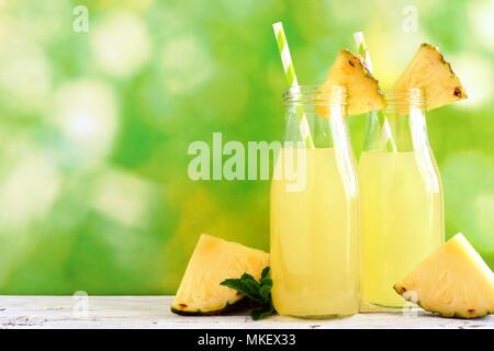 Succo di ananas in bottiglie di latte con un de-focalizzato sullo sfondo all'aperto Foto Stock