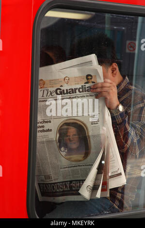 Vista dettagliata del maschio di " commuters " bus di lettura del quotidiano Guardian su un bus e facendo una news catch up Foto Stock