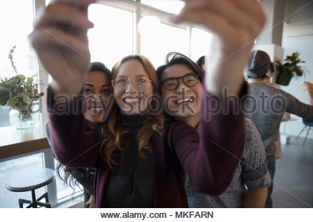 Sorridendo, entusiasta giovani amici prendendo selfie con la fotocamera del telefono
