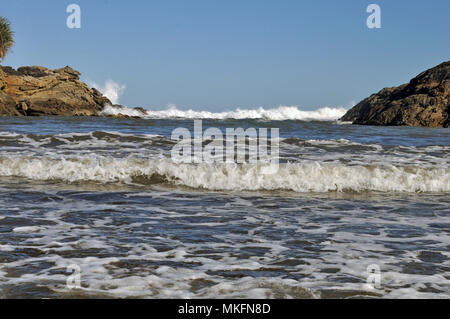 Le onde in arrivo invadere costante Bay sulla costa ovest della Nuova Zelanda Foto Stock