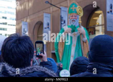 Un uomo di scattare una foto di San Patrizio Parade sul suo telefono cellulare Foto Stock