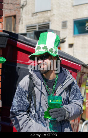 Uno spettatore a Montreal il giorno di San Patrizio sfilano indossando un cappello verde e bere la birra da un vetro verde Foto Stock