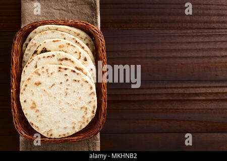 In casa di lievitato Naan indiano flatbread nel cestello, fotografato overhead sul legno scuro Foto Stock