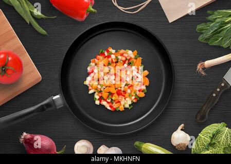 Friggere i pezzi di verdure in una padella. Preparare gli ingredienti per il piatto di testa. La cucina vegetariana. Vista dall'alto. Foto Stock