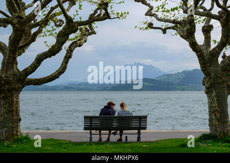 Uomo e donna seduti in una panchina di fronte al lago di Zugo, Svizzera, Europa Foto Stock