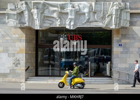 Un uomo su uno scooter giallo parcheggiato di fronte a una filiale UBS ufficio a Zurigo, Svizzera, Europa Foto Stock