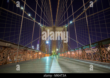 New York City Ponte di Brooklyn a Manhattan. Primo piano con grattacieli e dello skyline della città oltre il Fiume Hudson di notte. Foto Stock