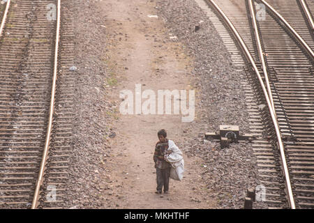 Nuova Delhi - India - 14 dicembre 2017. Un bambino povero è una camminata a piedi attraverso le ferrovie per cercare qualcosa da mangiare e le bottiglie di plastica da riciclare. Foto Stock