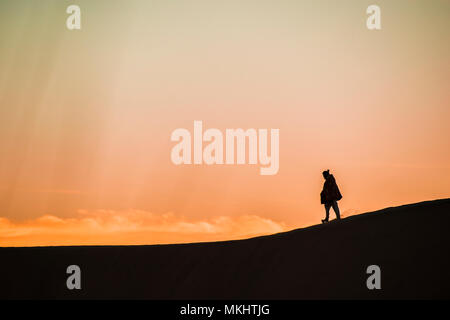 L'uomo cammina su un dune di sabbia del deserto al tramonto nel Rajasthan, India. Foto Stock