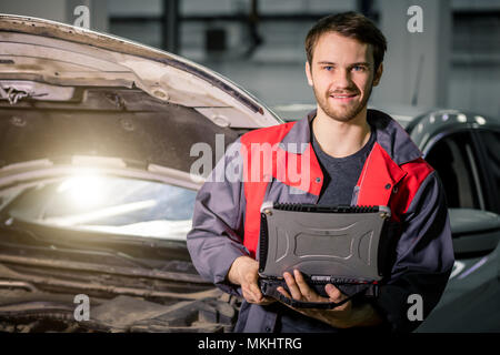 Mechanic utilizzando laptop in auto al garage di riparazione Foto Stock
