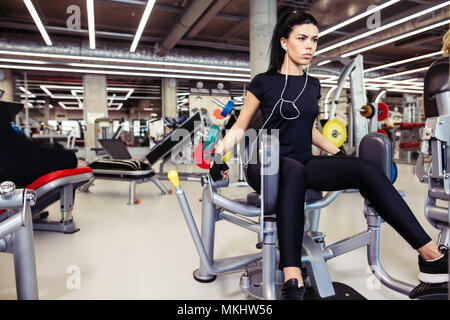 O di adduzione abductor machine. Montare la ragazza esercita le sue gambe in palestra Foto Stock