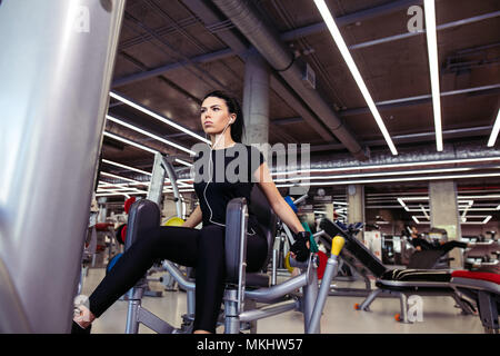 O di adduzione abductor machine. Montare la ragazza esercita le sue gambe in palestra Foto Stock