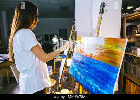 Artista femminile paintng foto su tela con vernici a olio nella sua officina Foto Stock