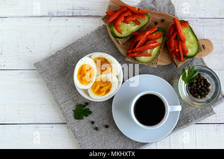 Una tazza di caffè forte (espresso), close-up e facile dieta colazione - uova sode e pane marrone con verdure fresche (cetriolo, paprika). La parte superiore vi Foto Stock