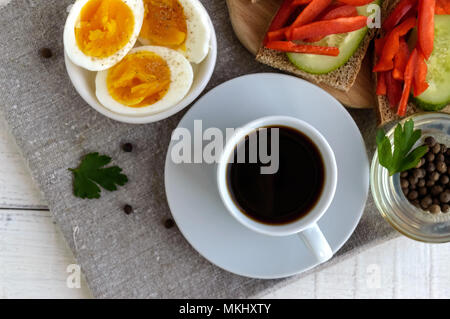 Una tazza di caffè forte (espresso), close-up e facile dieta colazione - uova sode e pane marrone con verdure fresche (cetriolo, paprika). La parte superiore vi Foto Stock