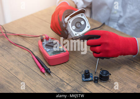 Il tecnico di riparazione telecamera TVCC sul tavolo. Foto Stock