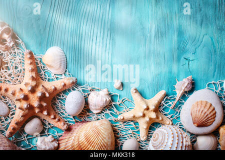 Orario estivo concetto con conchiglie e stelle marine blu su tavole di legno. Riposo in spiaggia. Sfondo con spazio di copia Foto Stock