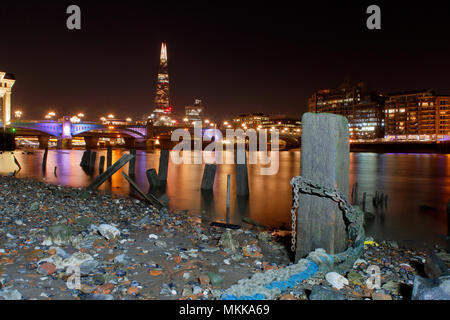 La Shard, Souwark Bridge, Queenshithe pier wrckage esposti a bassa marea, Londra notturna illuminata con luce artificiale imposta contro un cielo scuro. Foto Stock