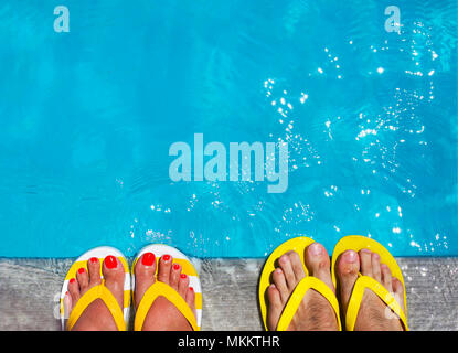 Piedi in flip flop su sfondo di pietra sul bordo della piscina. Estate Famiglia Concetto di vacanza Foto Stock