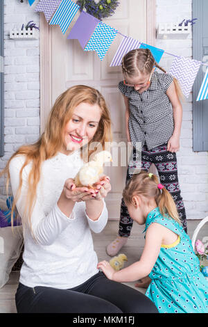 Famiglia gioca con piccoli polli sotto il portico della loro casa Foto Stock