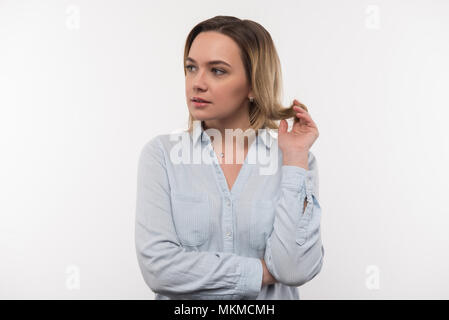 Bella donna pensosa toccando i suoi capelli Foto Stock