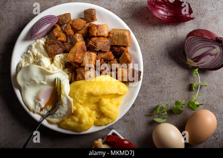 Tradizionale cibo Rumeno "Tochitura Moldoveneasca' fatta con carne di maiale, uova e formaggio con polenta sulla piastra Foto Stock