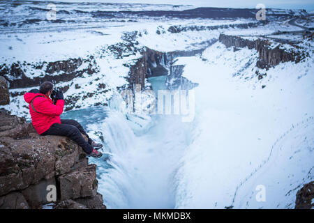 Uomo che scatta foto nella cascata dell'Islanda Foto Stock
