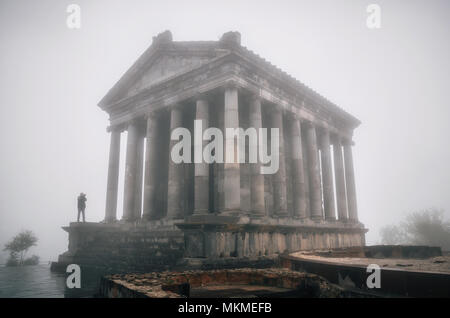 Garni ellenistico tempio pagano con silhouette di turistica prendendo foto nella nebbia, Repubblica di Armenia Foto Stock