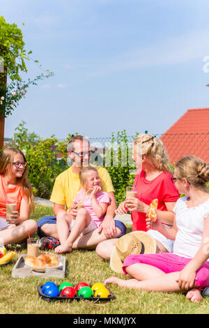 Famiglia avente picnic nel giardino davanti a casa loro Foto Stock