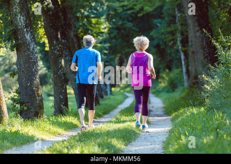 Lunghezza piena vista posteriore di una coppia senior jogging insieme all'aperto Foto Stock