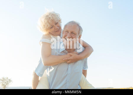 Felice l'uomo senior di ridere mentre si sta portando il suo partner sulla schiena Foto Stock