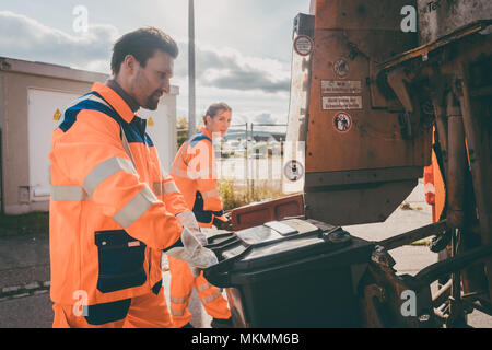 Garbage l uomo e la donna i bidoni di pulizia in camion dei rifiuti Foto Stock