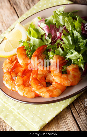 Gamberi fritti in salsa di soia e insalata fresca close-up su una piastra verticale. Foto Stock