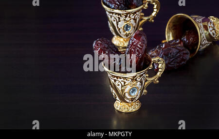 Ancora in vita con date e goldenTraditional caffè arabo impostato con coppa mini. Sfondo scuro. Copia dello spazio. Foto Stock