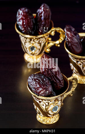 Ancora in vita con date e goldenTraditional caffè arabo impostato con coppa mini. Sfondo scuro. Foto verticale. Foto Stock