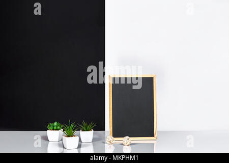 Telaio in legno nero con posto per il testo. Mock up. Elegante sala interna. Pianta verde in un vaso bianco su bianco-nero e sfondo a parete