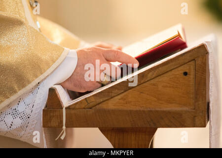 Sacerdote cattolico la lettura di un libro a massa Foto Stock