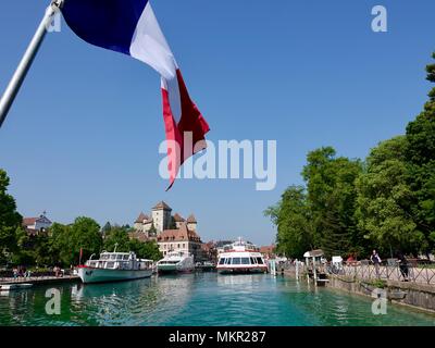 Crociera barche ormeggiate lungo il fiume Thiou sul bordo del lago di Annecy con la città vecchia di Annecy in background e molti turisti passeggiate lungolago, Francia Foto Stock