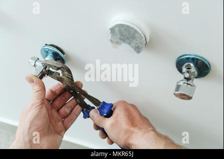 Plumber installa angelo valvola servendosi di una pinza chiave. Foto Stock