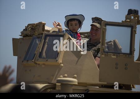 CATC CAMP FUJI, Shizuoka, Giappone- Lance Cpl. Cassandra Petrich in posa per una foto con un bambino durante la Flightline Fuji Festival Maggio 4 sui bracci combinato Training Center Camp Fuji, Giappone, 5 maggio 2018. La Flightline Festival è un evento annuale destinato a portare i membri della comunità locale su base per costruire relazioni e amicizie e mostrare i Marines' operazioni quotidiane. Non appena i cancelli aperti, fotografi e famiglie hanno gareggiato su per la collina verso la statica visualizza. Petrich è una Mariposa, California, nativo, e un motore di operatore di trasporto con il combattimento il battaglione della logistica 4, pettine Foto Stock