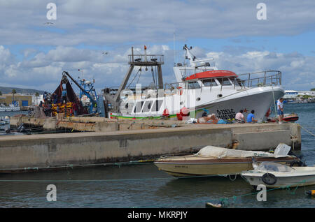 L'equipaggio di un portamonete con sciabica raccoglie le sue reti in Olhao porto di pescatori, Algarve, Portogallo meridionale Foto Stock