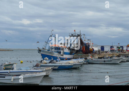 L'equipaggio di un portamonete con sciabica raccoglie le sue reti in Olhao porto di pescatori, Algarve, Portogallo meridionale Foto Stock