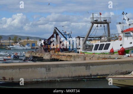 L'equipaggio di un portamonete con sciabica raccoglie le sue reti in Olhao porto di pescatori, Algarve, Portogallo meridionale Foto Stock