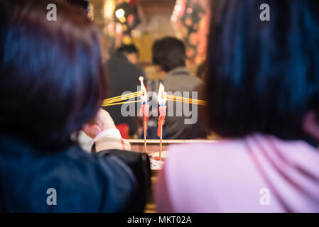 Due donne luce bastoncini di incenso da candele accese pregando nel famoso tempio Man Mo, Sheung Wan, Hong Kong Foto Stock